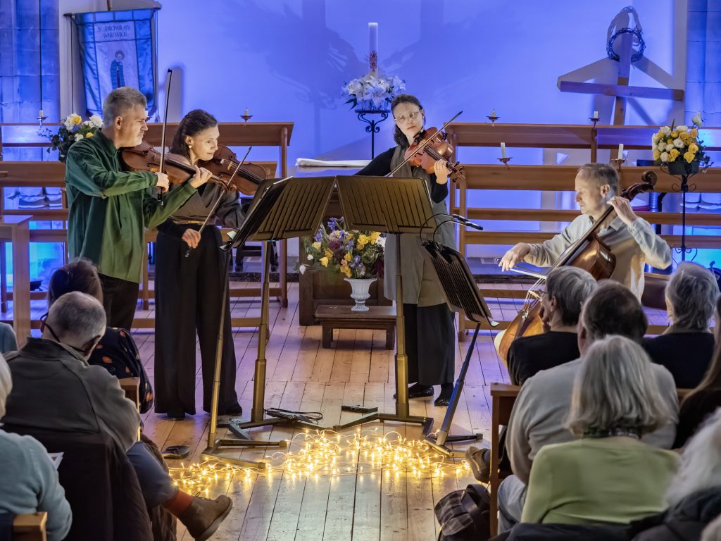 Swan players performing with a blue light behind them and candles