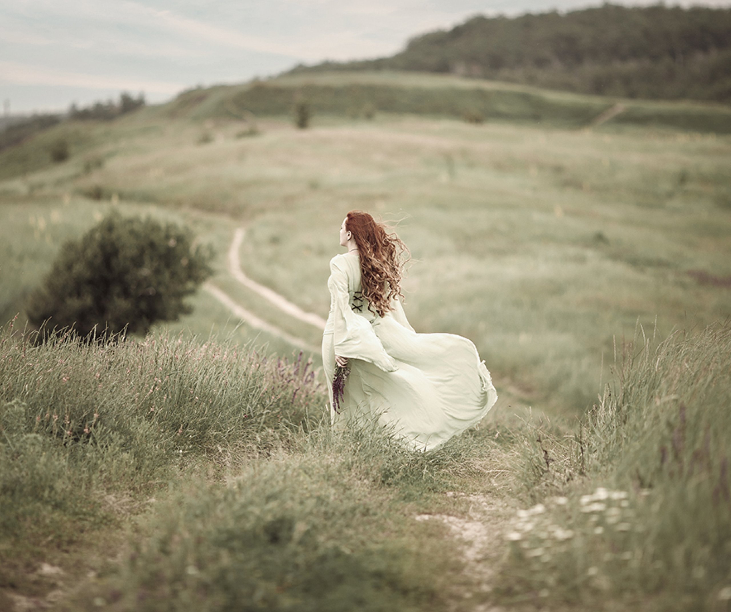 Romantic Horizons depicts a red head in a floaty dress walking through a meadow