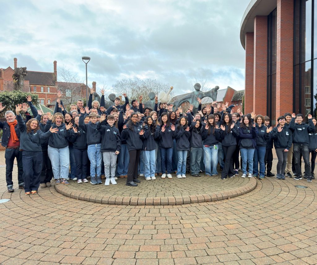 Swan Youth Orchestra from February 2026 standing in a group waving - a Swan toy is being held aloft